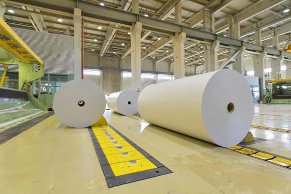 Large rolls of recycled fibre material in an industrial paper processing facility supported by efficient mixing processes. 